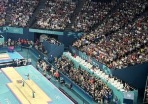 Suni Lee performs on the balance beam in front of a large U.S. crowd during the 2024 Olympic Summer Games in France. Photo by Matt Traub/SportsTravel